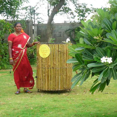 Daily Dump Bamboo leaf composter 32 inches diameter in use for composting dried leaves with lady in red sari standing next to it.